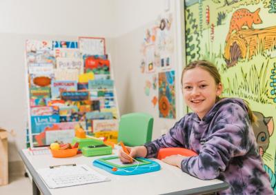 A young girl in playing with some toys and smiling.