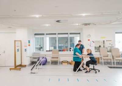 A physiotherapist providing a patient therapy to help them walk.