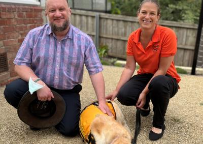 Facility Dog Ziggie with consumer Leander and handler Rachel